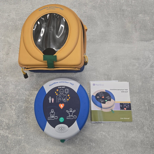 HeartStart AED device with carrying case and user manual on a gray surface