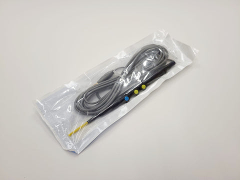 A black electrosurgical pencil with a yellow connector, sealed in a clear plastic bag.