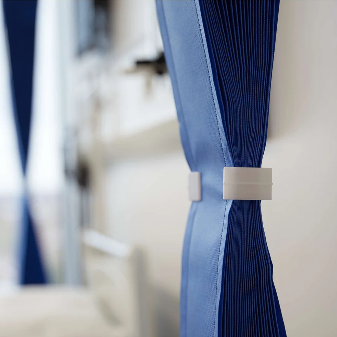 Blue pleated curtain with a white tie-back against a blurred indoor background