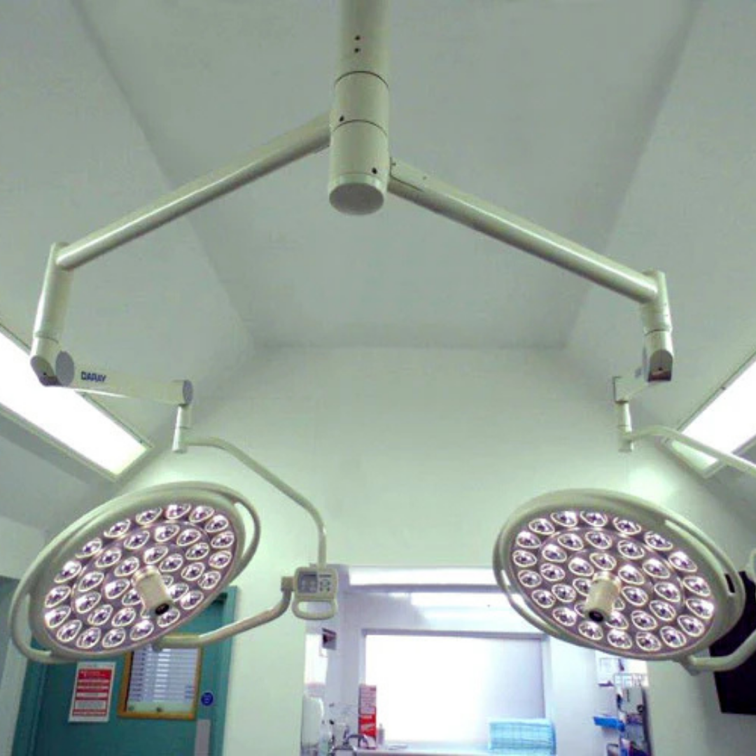 Two surgical lights hanging from the ceiling in a medical setting.