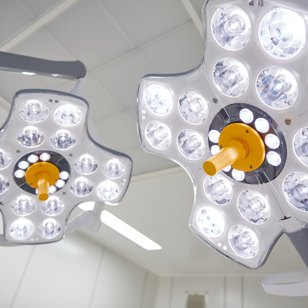 Two surgical lights hanging from the ceiling in a medical setting.