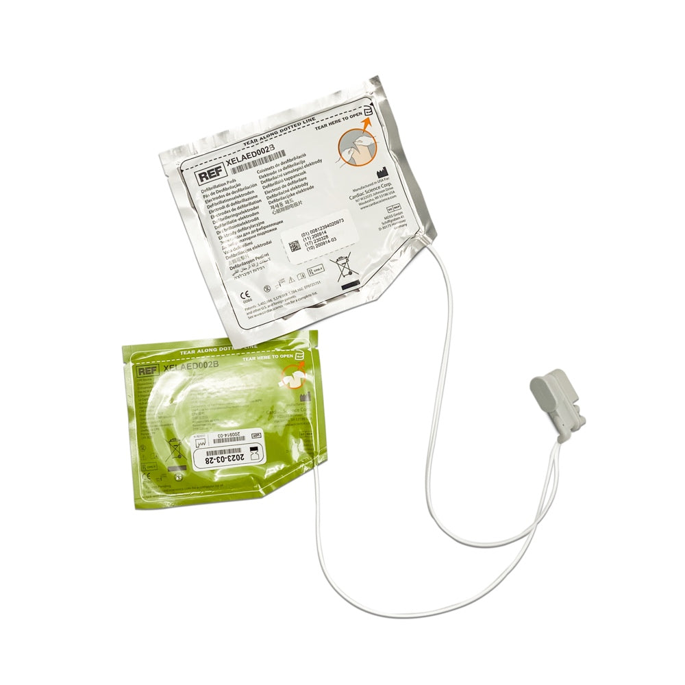 A pair of green adult defibrillator pads with a white label and a grey cable, attached to a CPR device.