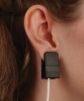 An ear clip SpO2 sensor from Nonin being worn on an ear, with a white cable connecting to the sensor.