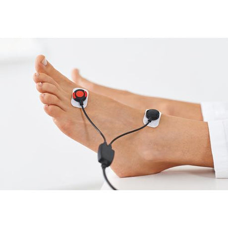 A foot with a red and black cloth electrode connected to a seca mBCA body composition monitor.